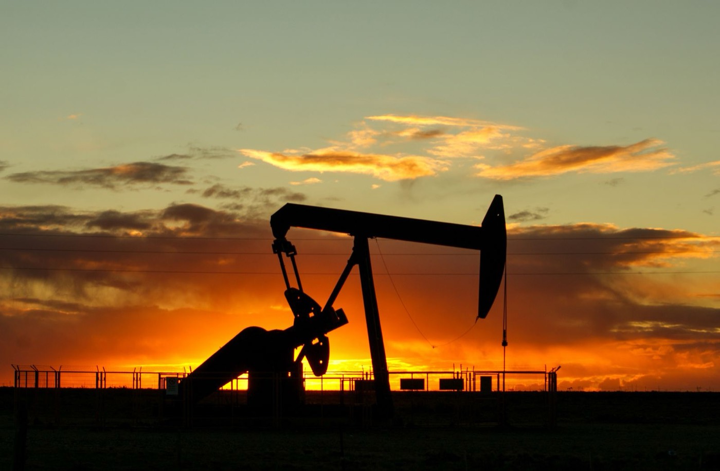 Oil pumpjack silhouetted against an amber dusk sky